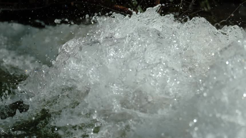 A powerful torrent of water crashes and foams in an extreme slow-motion close-up