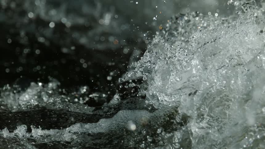 A super slow-motion close-up captures the powerful, churning motion of whitewater rapids