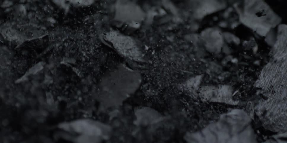 A macro shot of dark charcoal pieces shaking and bouncing in slow motion