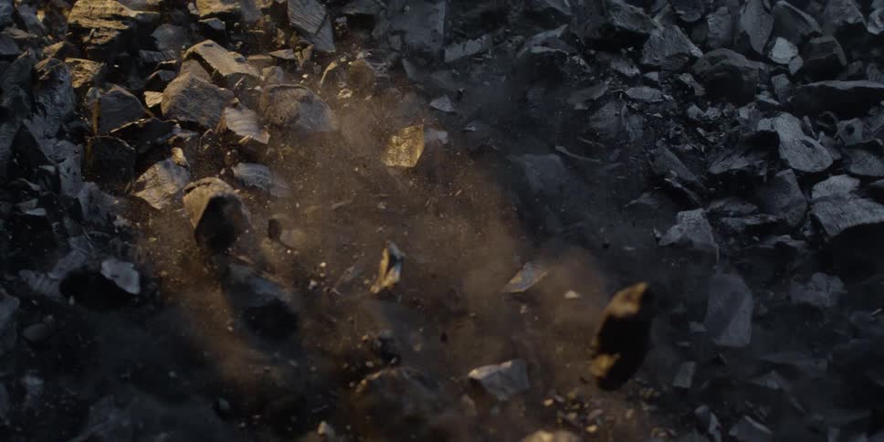 Chunks of coal and dust explode upwards in dramatic slow motion