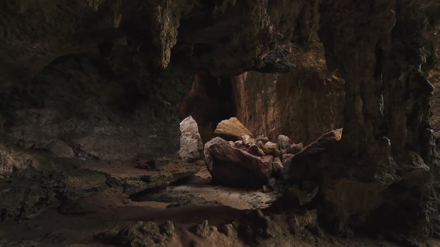 A slow push-in shot reveals the dark and mysterious interior of a natural rock cave