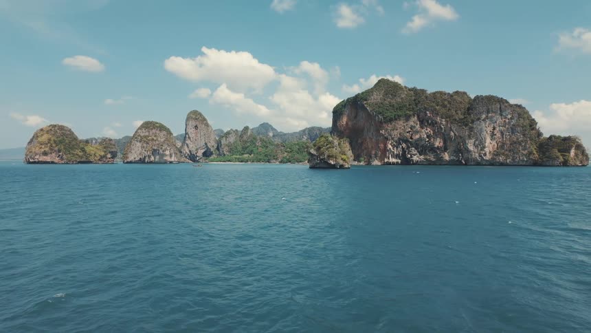Majestic tropical islands with lush greenery rise from the calm blue ocean under a partly cloudy sky