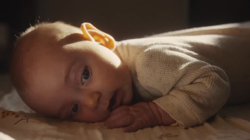 Close-up of a sweet newborn baby lying on its tummy, bathed in soft, natural light