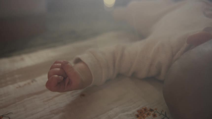 A dreamy close-up shot of a newborn baby's hand twitching and closing as they sleep peacefully
