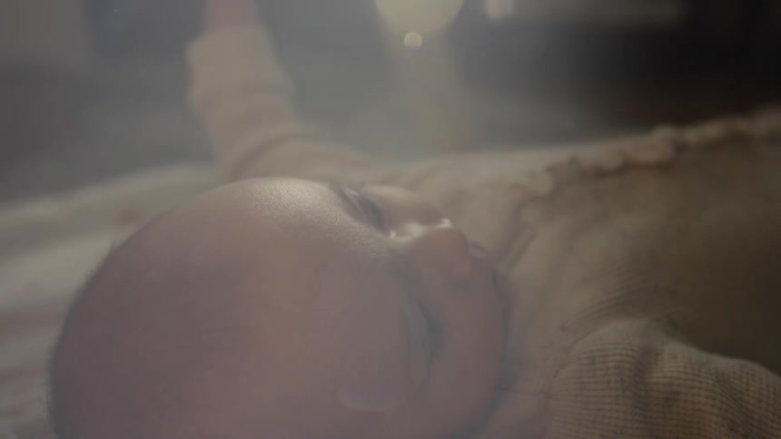 A dreamy and ethereal close-up of a newborn baby's face as they lay awake peacefully in soft, gentle light