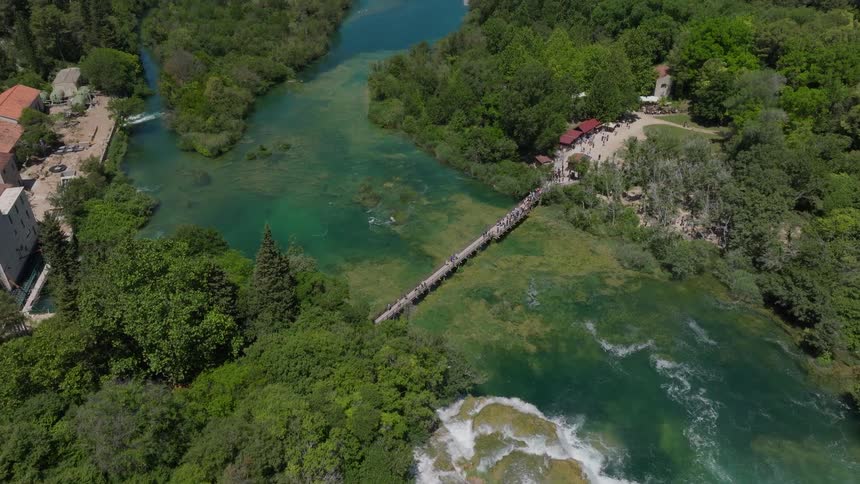 A stunning aerial view ascends over the Skradinski Buk waterfall, revealing the lush green valley and turquoise river of Krka National Park in Croatia