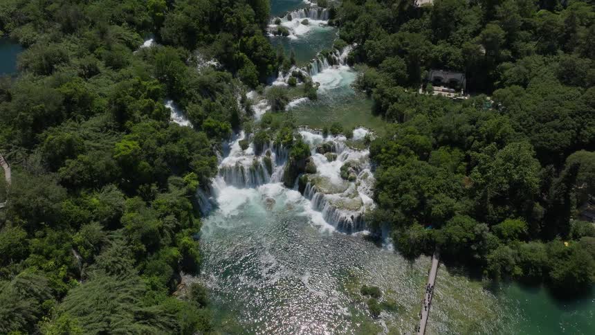 An awe-inspiring aerial view reveals the majestic tiered waterfalls of Krka National Park in Croatia, surrounded by a lush green forest