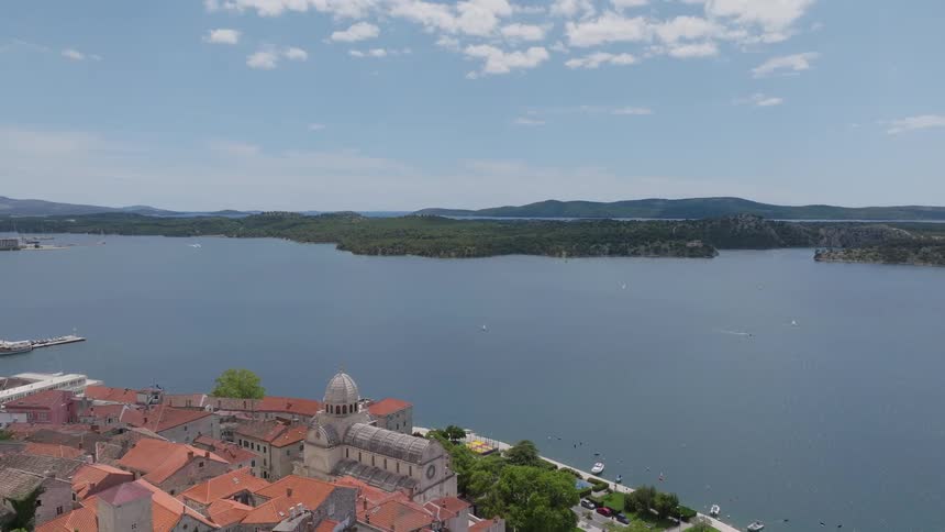 An aerial shot begins on a couple admiring the view before rising to reveal the stunning cityscape of Sibenik, Croatia, and its beautiful bay