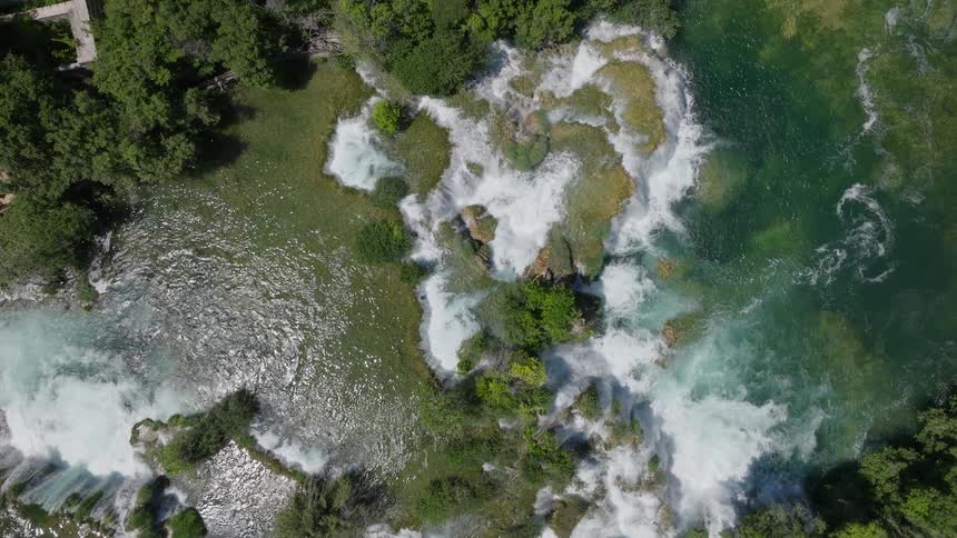 An awe-inspiring top-down aerial view reveals a majestic river branching into numerous powerful waterfalls amidst a dense green forest
