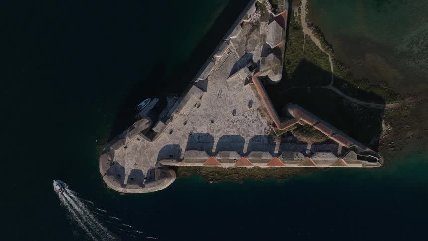 A mesmerizing top-down aerial view reveals the historic St. Nicholas Fortress as a small boat cruises by on the calm sea