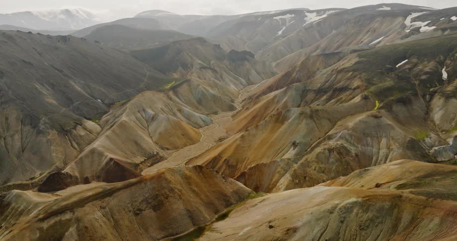 An aerial view reveals the vast, colorful, and mineral-rich rhyolite mountains of the Landmannalaugar region in the Icelandic highlands