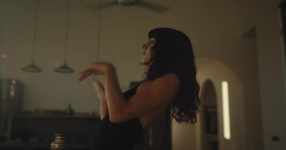 A woman dances gracefully and expressively in slow motion in her sun-drenched apartment, with warm light creating a cinematic lens flare