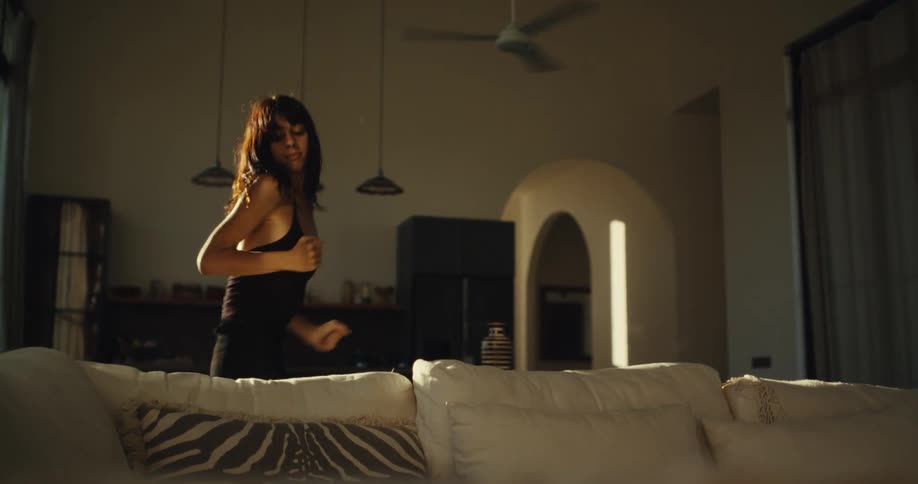 A carefree woman dances expressively in slow motion by herself in her warmly lit living room