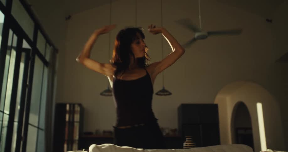 A free-spirited woman dances expressively by herself in the golden light of her modern home