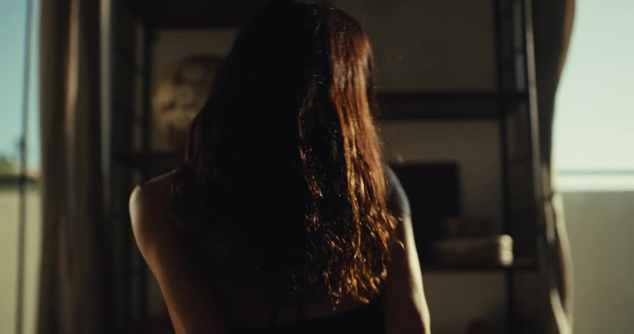 Slow motion shot of a carefree woman with flowing hair dancing joyfully in her sunlit apartment