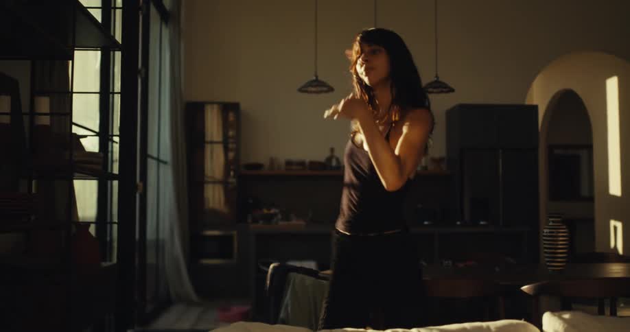 A graceful woman dances freely in her sunlit home, moving expressively in the warm afternoon light
