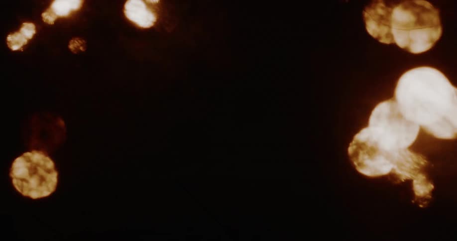 Abstract background of floating, warm, sepia-toned bokeh lights against a dark, textured backdrop