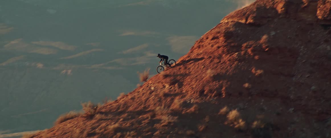 An extreme mountain biker fearlessly navigates a steep red rock descent on their bicycle