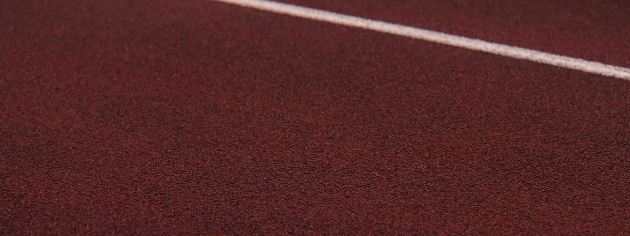 Close-up of a track and field athlete's foot pivoting in a specialized shoe on a red running track