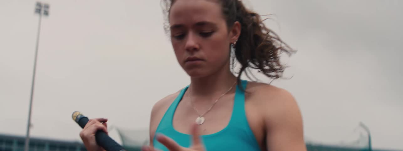 A determined female pole vaulter adjusts her grip and focuses before her jump in a slow-motion close-up