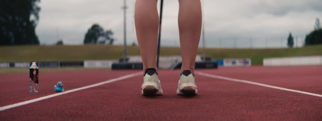 Low angle, slow motion close-up of a female pole vaulter's feet running on a track before a jump