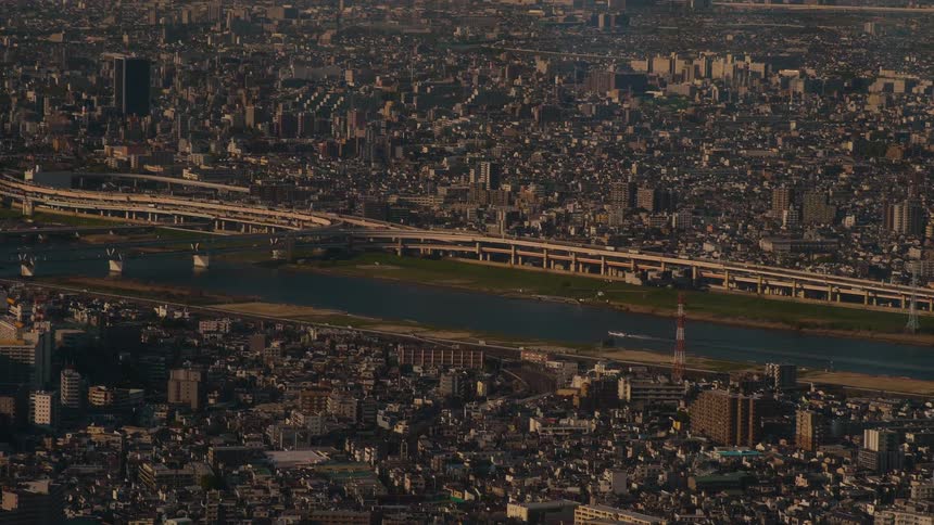 High-angle timelapse of a vast urban cityscape with a river and bustling highway system during the day