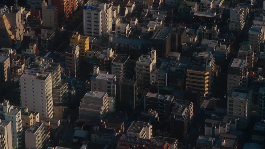 High-angle timelapse captures the rising sun casting long shadows across a dense city as morning traffic begins to flow through the streets