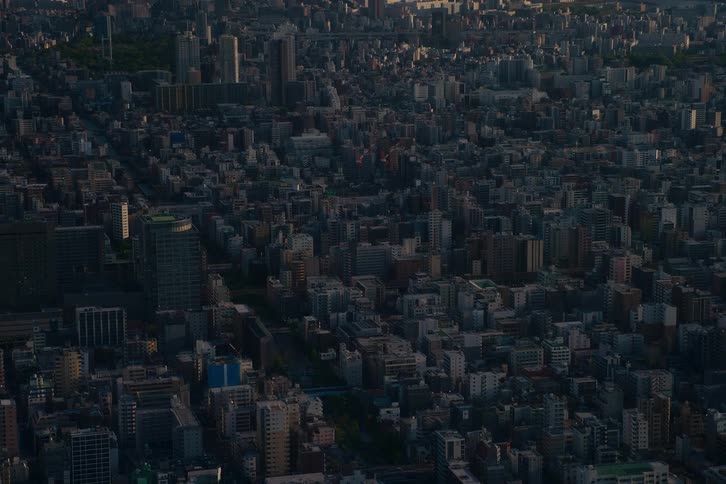 An expansive aerial view of a sprawling, dark urban metropolis during the quiet hours of dawn