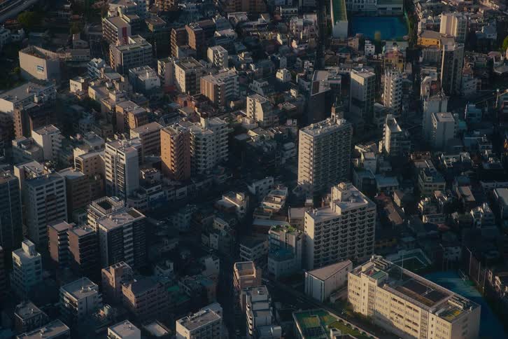A high-angle timelapse captures the morning light sweeping across a dense urban landscape in Tokyo