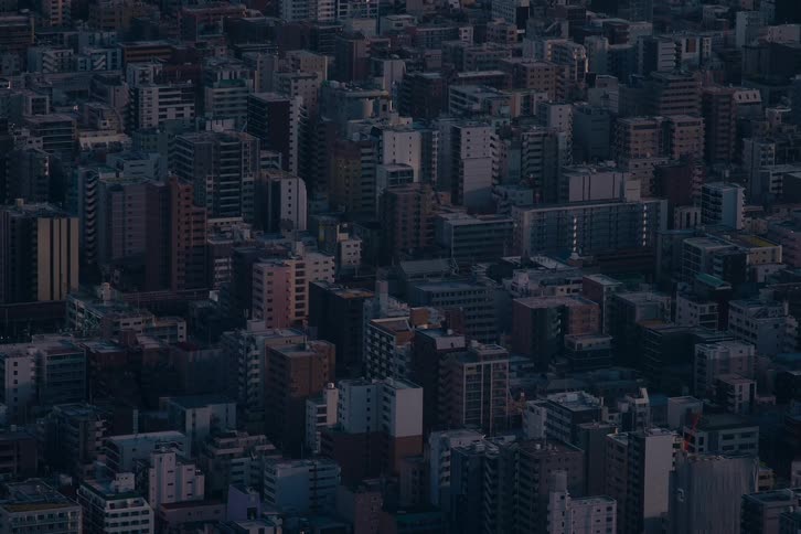 A static, high-angle view captures the dense urban sprawl of a major city as the buildings fade into the twilight