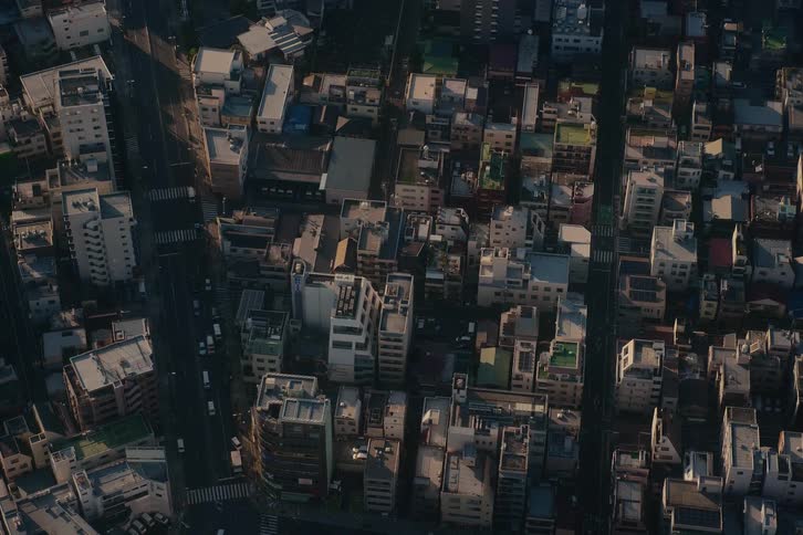 A static high-angle view captures the dense urban landscape of a city with light traffic during the golden hour