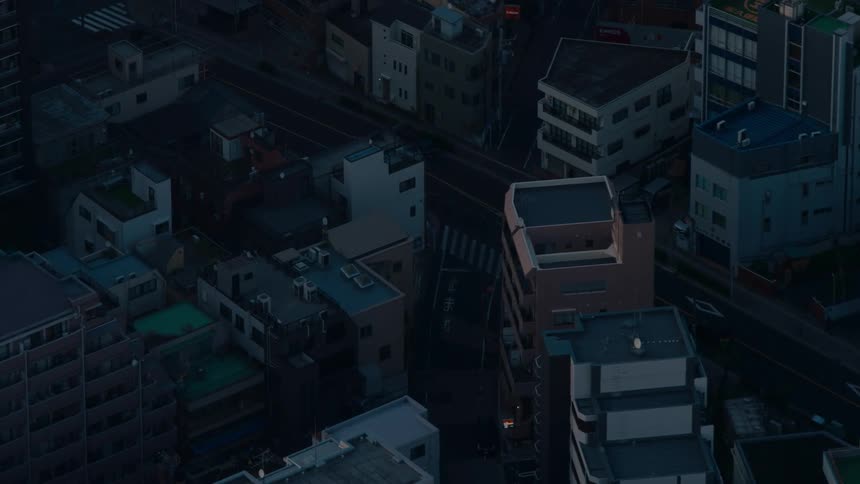 A high-angle view of a quiet city intersection with minimal traffic as day turns to night
