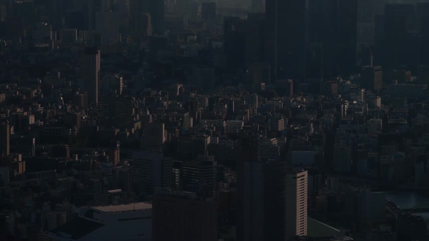 A moody, atmospheric high-angle view of a vast cityscape shrouded in darkness before sunrise