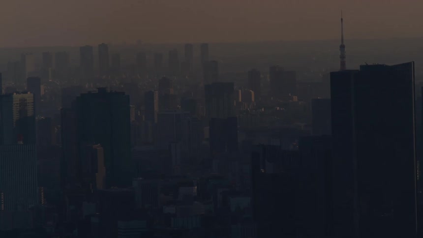 An atmospheric and moody wide shot of a hazy Tokyo cityscape just before sunrise