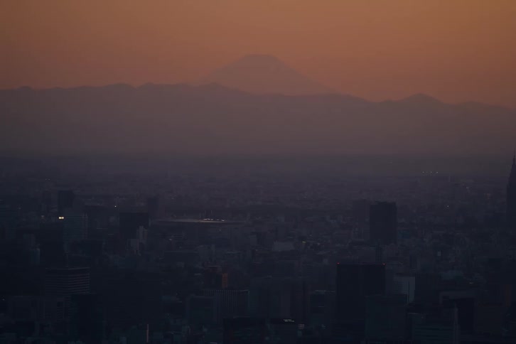The silhouette of Mount Fuji is seen over the sprawling city of Tokyo during a beautiful, hazy sunset