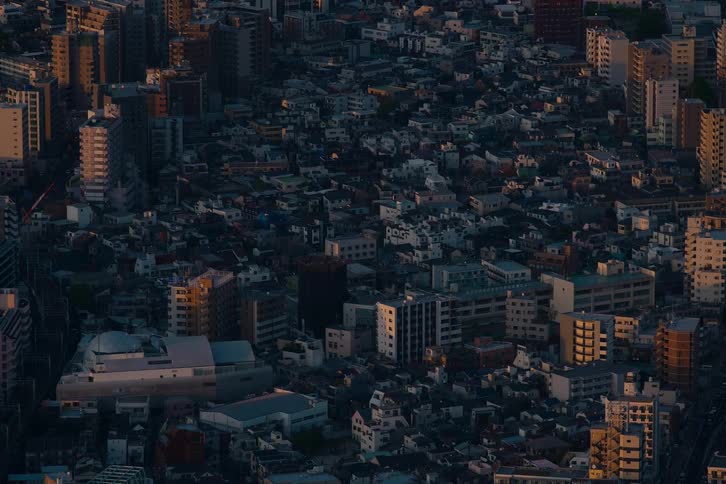 A static high-angle view of a dense urban city as the golden hour sun illuminates the buildings and casts long shadows