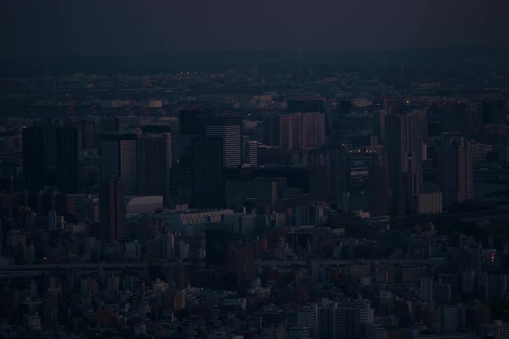 An aerial view of a sprawling metropolis just after sunset, as the city lights begin to turn on in the twilight