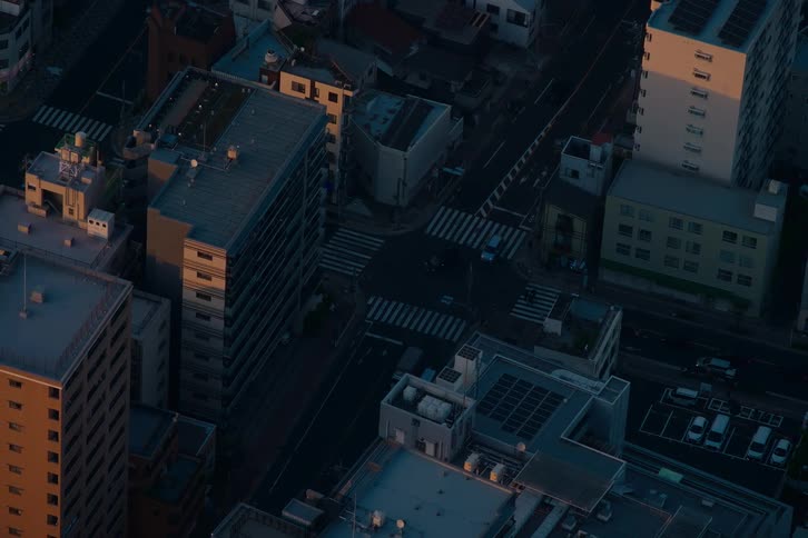 An atmospheric high-angle view captures the quiet flow of traffic through a city intersection at dusk