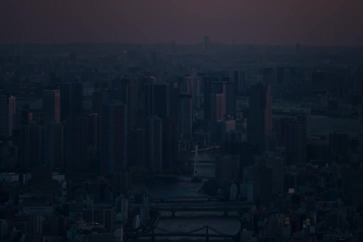 A moody aerial view of a sprawling city skyline during the quiet twilight hours before dawn