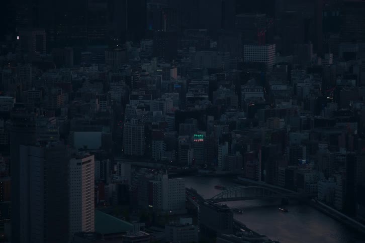 A tranquil high-angle view of the Tokyo cityscape at dusk, where boats navigate the river and city lights begin to emerge