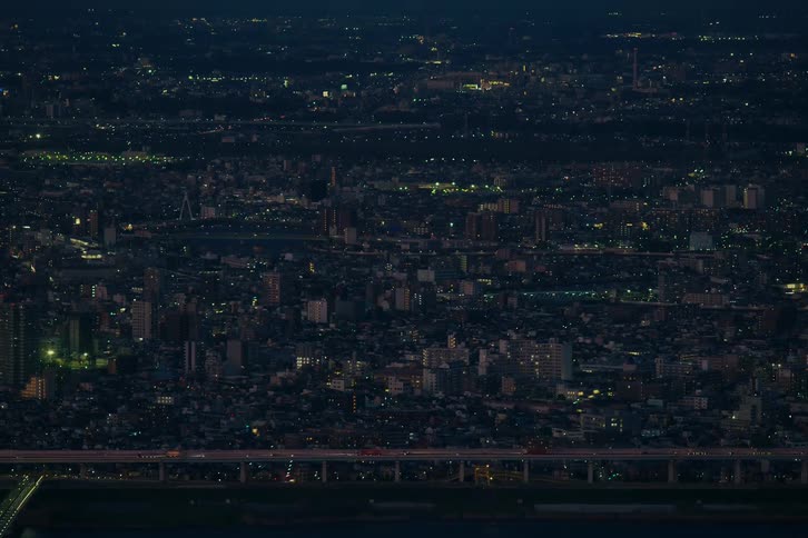 A stunning timelapse of a vast metropolis at night, with countless city lights twinkling and traffic streaming across a busy highway