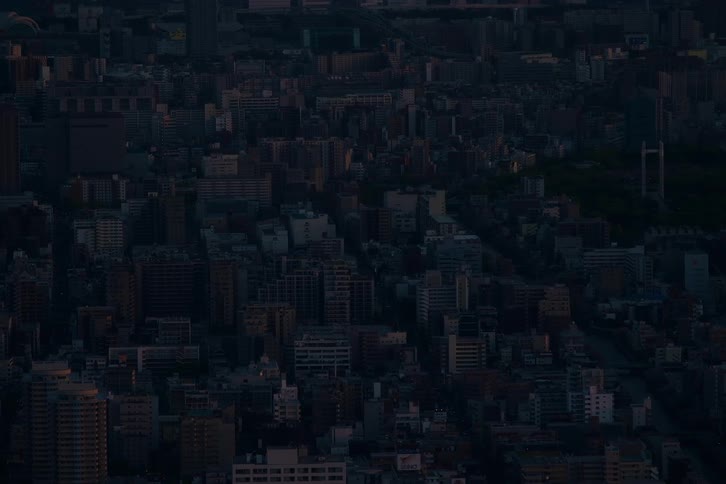 An expansive aerial view of a dark city with buildings barely visible in the twilight hours