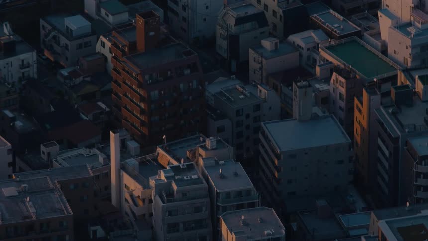 Golden sunset light moves across the rooftops of a dense Japanese city in this stunning aerial time-lapse