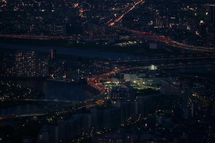 A stunning high-angle view captures the twinkling lights and bustling highways of a sprawling metropolis at night