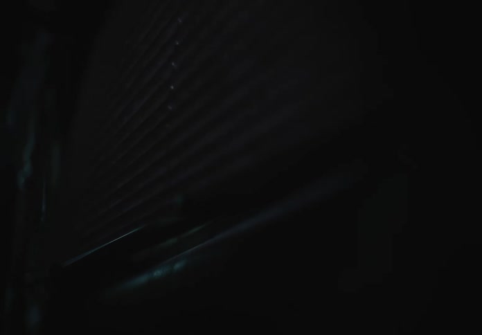 A low-angle close-up shot shows a glowing orange light passing over a dark, ribbed surface