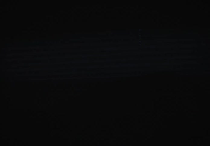 A slow pan from the dark rear of a van reveals a person driving through a quiet suburban street at night