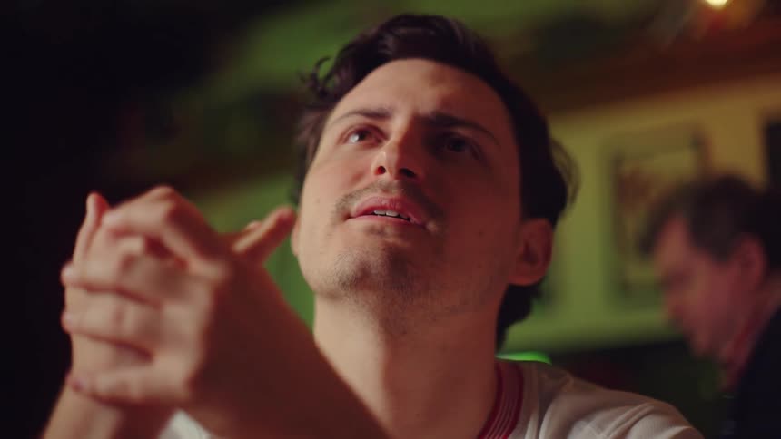 An anxious man watches a sports game on TV, his face filled with hope and desperation in slow motion
