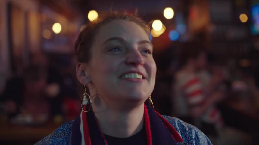 A female sports fan's face shows the emotional rollercoaster of watching her team play in a crowded bar