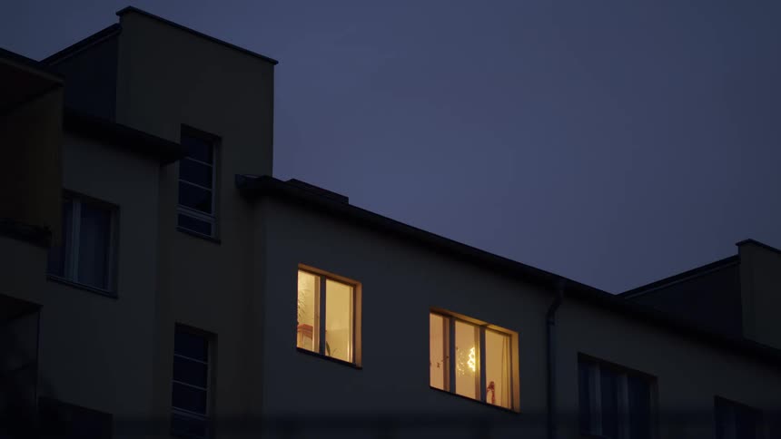 Warm light glows from apartment windows against the dark twilight sky