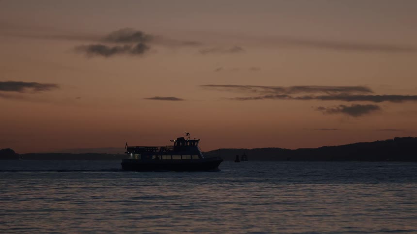 A passenger ferry glides across the tranquil water during a beautiful twilight evening